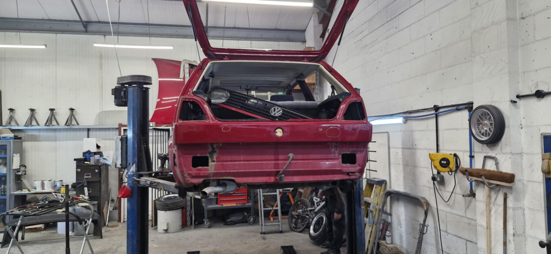 Red VW Golf stripped down on the workshop lift